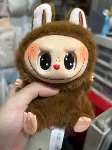 Brown fluffy Lafufu doll held in hand